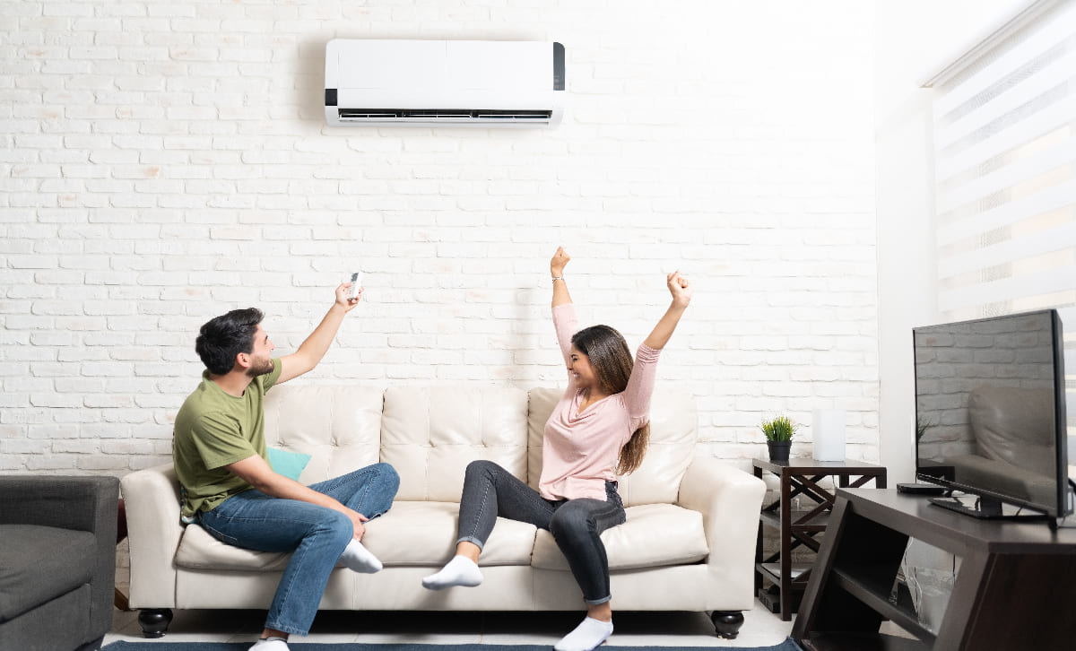 Cooling Services Page - Image 1 Couple Sitting Below Mini Split On Sofa At Home