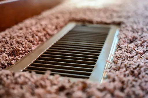 Focus on floor vent in room with carpet